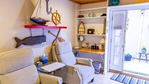 Un salon chaleureux avec un canapé, une petite table, une bibliothèque et des éléments de décoration sur le thème de la marine.