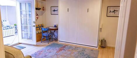 A room with a ceiling fan, a large white closet, a dining table with chairs, and a colorful rug.