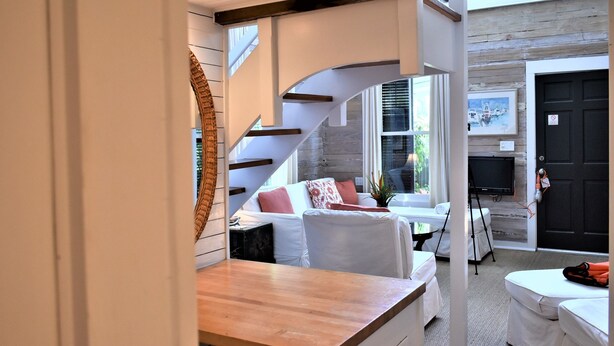 Ein modernes Interieur mit Treppe, einer Sofagarnitur, einem Holztisch und einem Fernseher.
