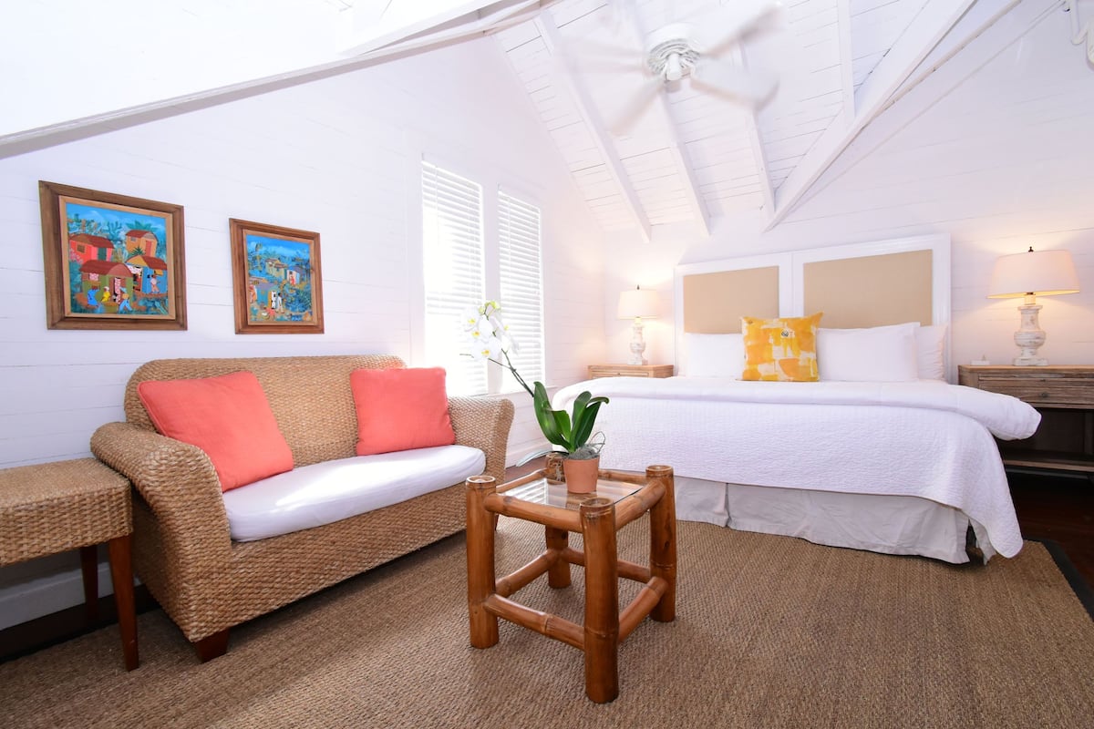Ein Schlafzimmer mit einem Bett, einer Couch, einem kleinen Tisch und zwei Bildern an der Wand.