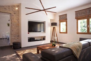 A modern living room with a stone accent wall, a mounted TV, a wooden coffee table, a sofa, and a floor lamp.
