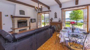 A living room with a fireplace, a large black sectional sofa, and a dining table set for six.