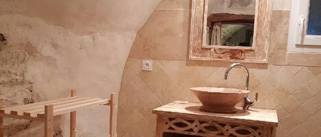 Une salle de bain au style rustique, avec un meuble-lavabo en bois, un grand miroir et une étagère intégrée.