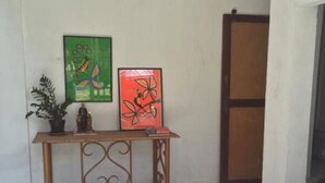 Habitació amb sòl de rajoles, una taula de consol de fusta amb dues obres d'art emmarcades, una planta en test i un sofà.