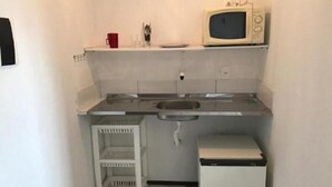 Una cuina compacta amb microones, rentapelats i nevereta petita.