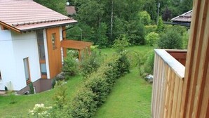 Une vue d’un quartier résidentiel avec une pelouse bien entretenue, une clôture en bois et une maison avec un toit rouge.