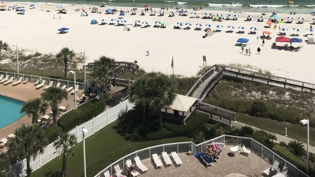 A beach with numerous umbrellas and sun loungers, a pool area, and a view of the ocean. - Direct Ocean View from the top floor! (Orange Beach)