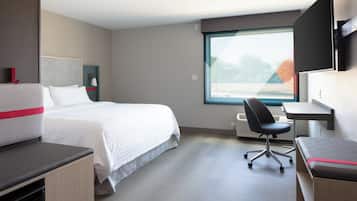 Een hotelkamer met een bed, een bureau, een stoel en een groot raam.