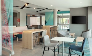 A modern lounge area with seating, a counter, and a TV screen. - avid hotels Madison - Monona by IHG (Madison)
