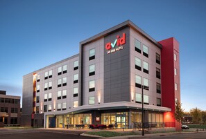 A modern hotel building with a prominent 'avid' sign, multiple windows, and a well-lit entrance area. - avid hotels Madison - Monona by IHG (Madison)