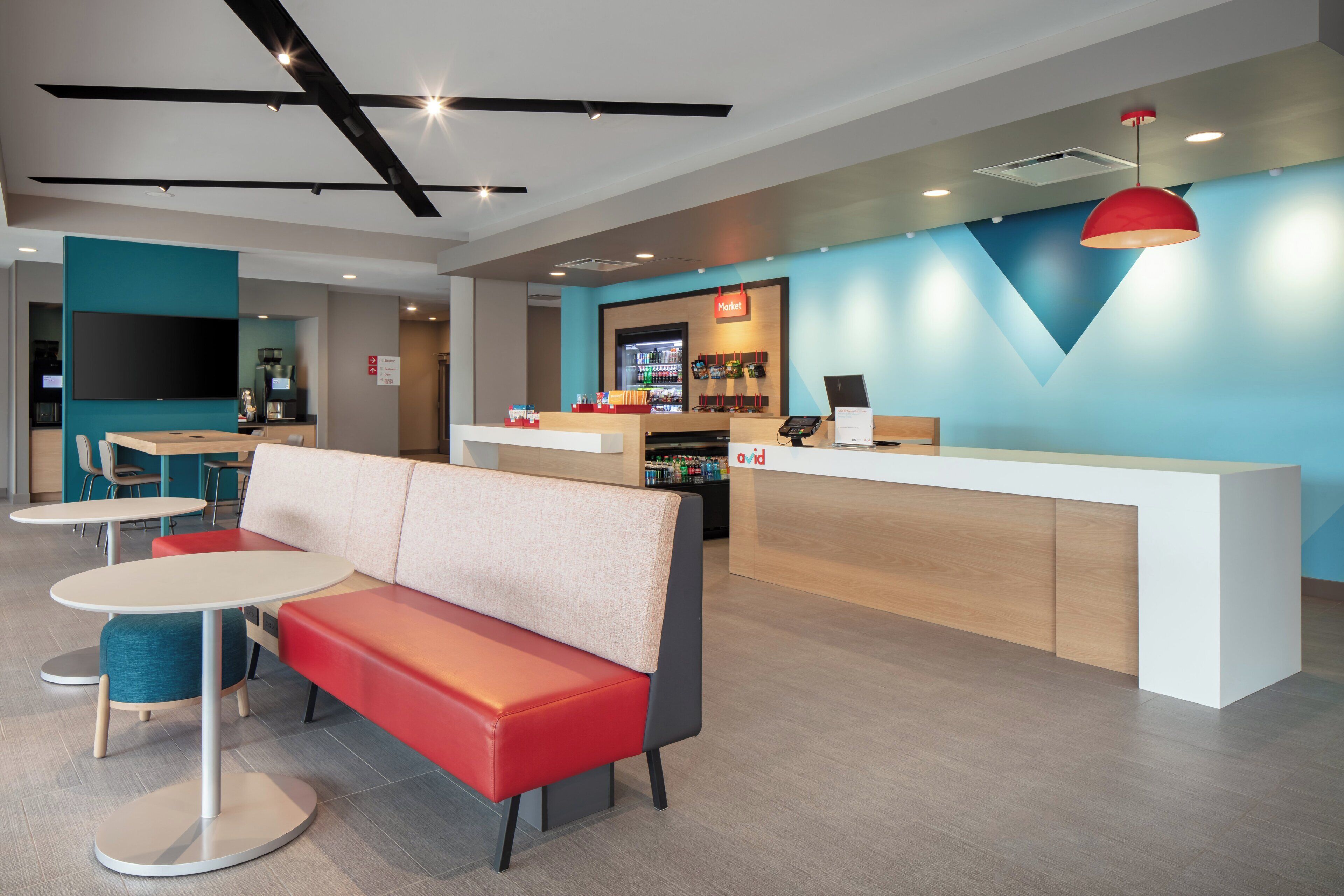 A modern hotel lobby with a seating area, a reception desk, and a coffee machine.