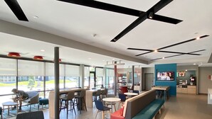 A modern interior with seating areas, a counter, and a television screen. - avid hotels Beaumont by IHG (Beaumont)