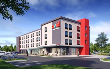 A modern hotel with a prominent red and grey facade, multiple floors, and a covered entrance area.
