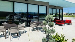 An outdoor seating area with tables and chairs, a small tree, and a red bench. - avid hotels Beaumont by IHG (Beaumont)
