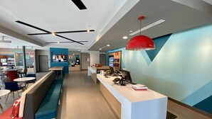 A modern reception area with a white counter, blue seating, and a red pendant light. - avid hotels Beaumont by IHG (Beaumont)