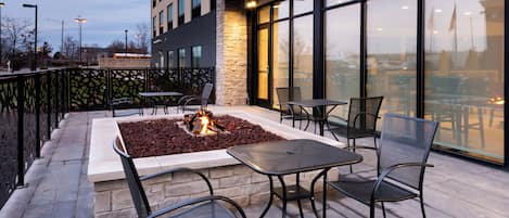 An outdoor patio with a fire feature, seating, and a view of a cityscape.