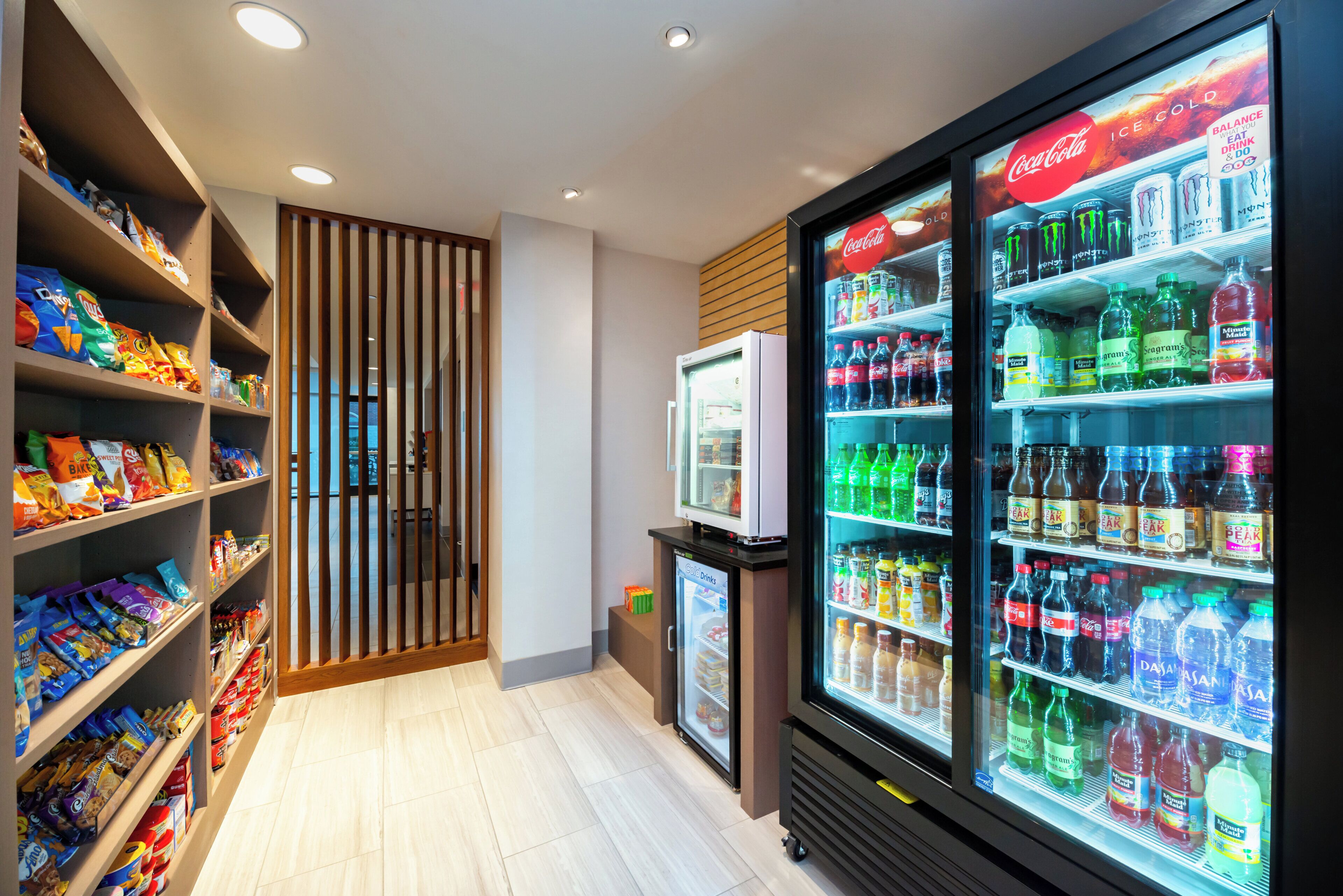 A snack and beverage area with shelves stocked with various snacks and a refrigerated display case with beverages.