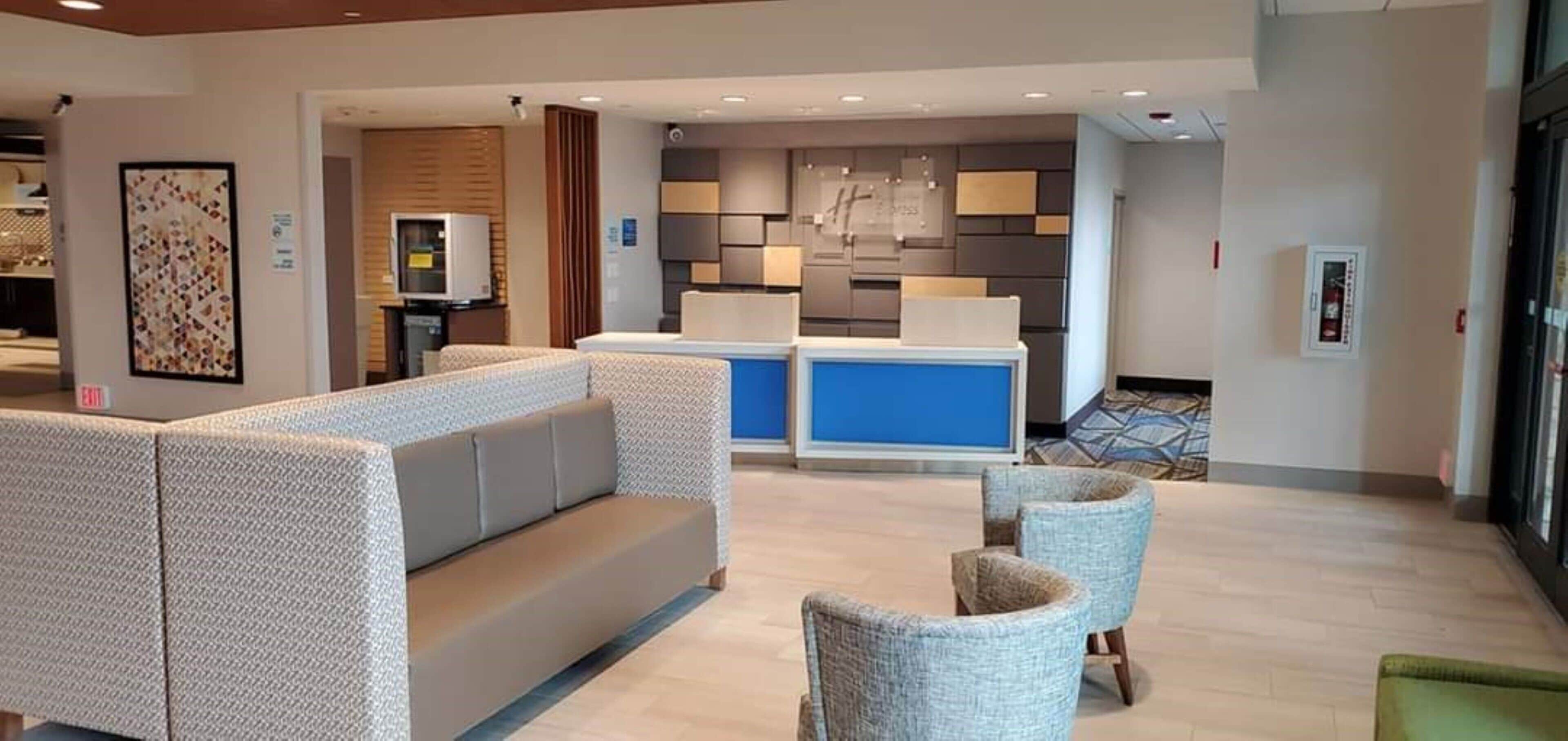 A hotel lobby with a reception desk, seating area, and a wall-mounted clock.