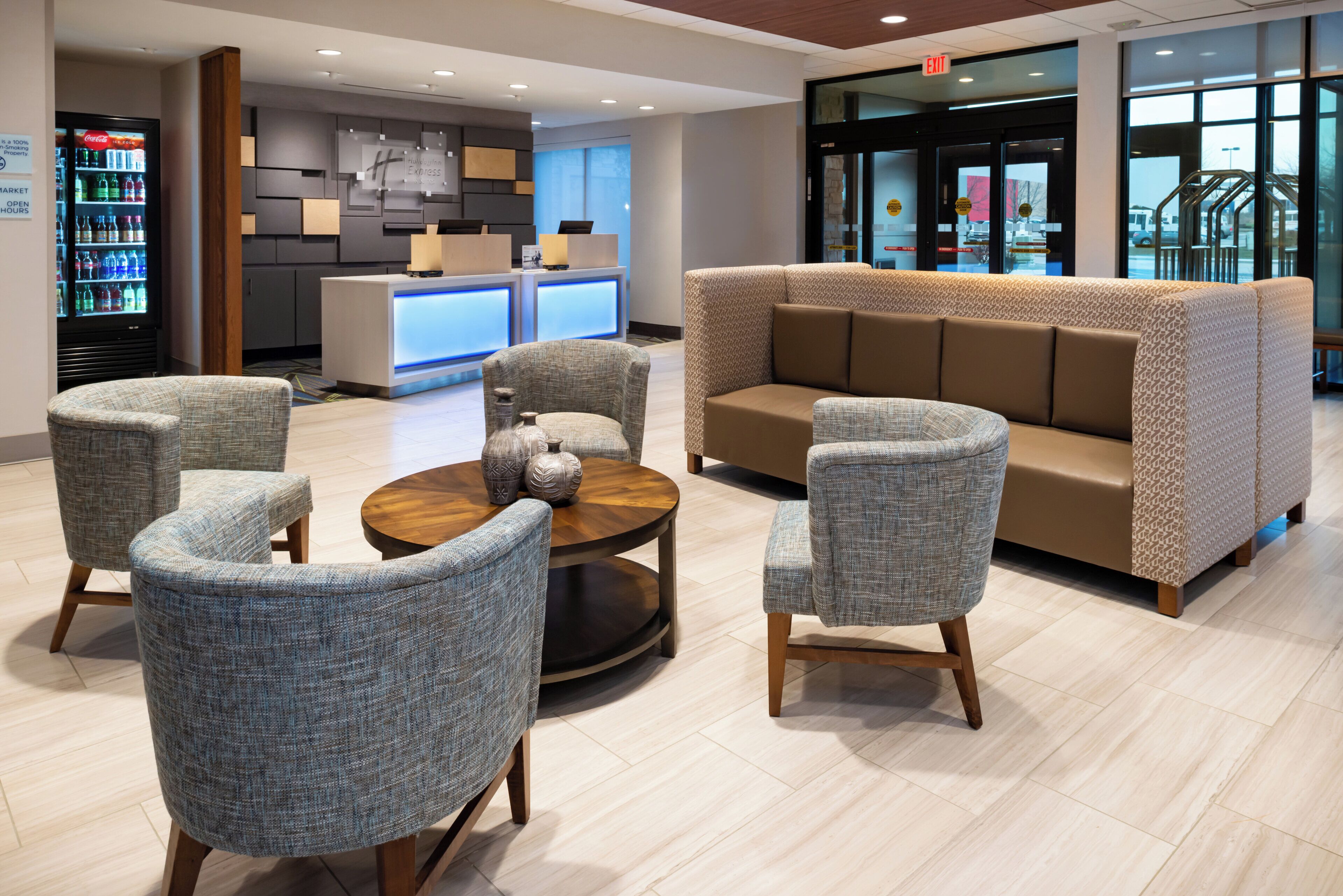 A lobby with a reception desk, seating area, and a Coca-Cola refrigerator.