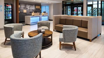 A lobby with a reception desk, seating area, and a Coca-Cola refrigerator.