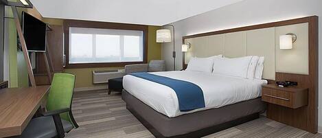 A hotel room with a large bed, a desk with a chair, a TV, and a window with a view.