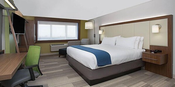 Een hotelkamer met een groot bed, een bureau met stoel, een televisie en een raam met uitzicht.