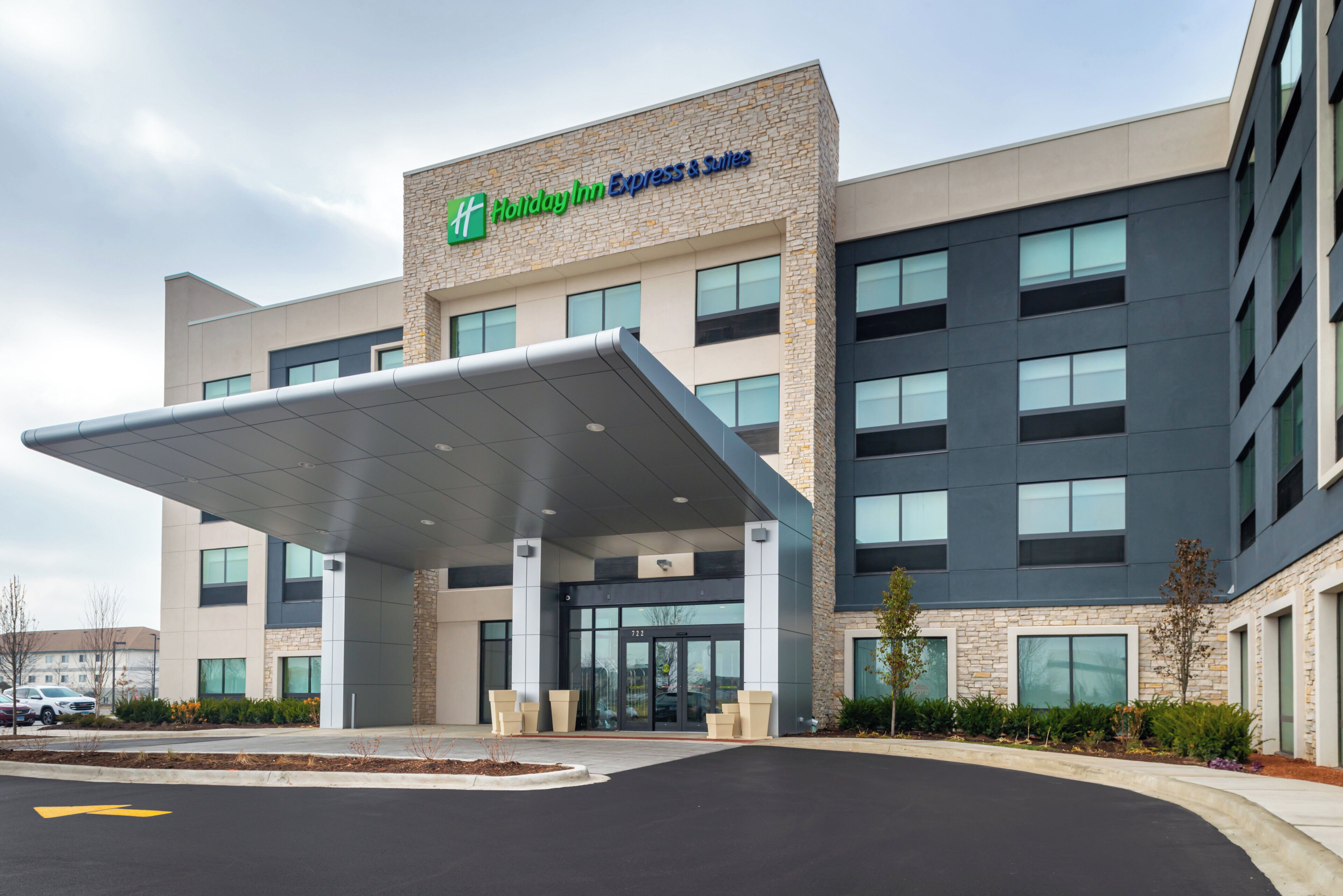 A Holiday Inn Express & Suites building with a covered entrance and a parking lot.