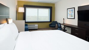 A hotel room with a large bed, a desk with a chair, a flat-screen TV, a window with a view, and a wall-mounted lamp. - Holiday Inn Express & Suites Romeoville - Joliet North by IHG (Romeoville)