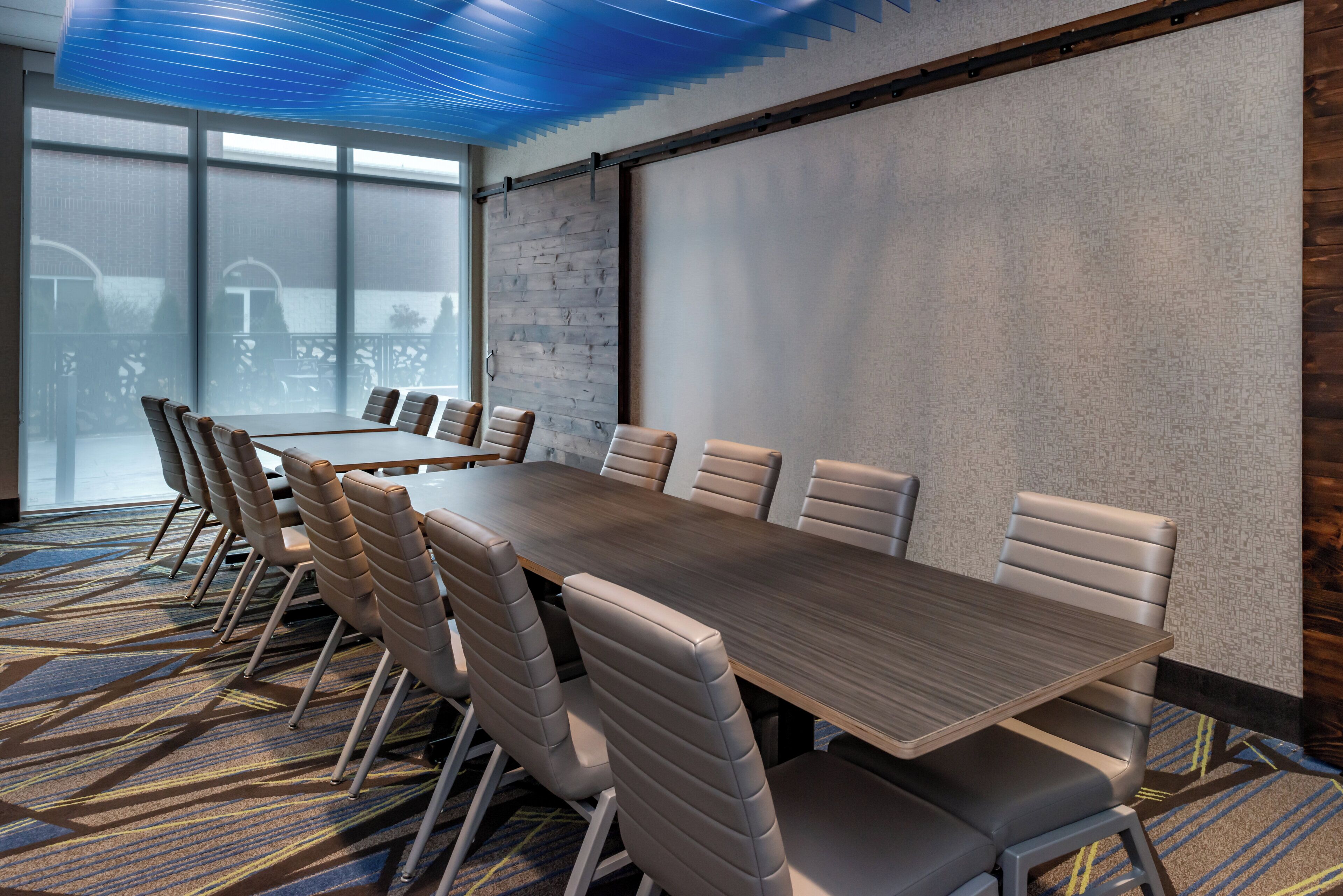 A conference room with a long table, multiple chairs, and a large window.