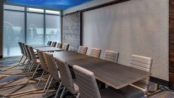 A conference room with a long table, multiple chairs, and a large window.