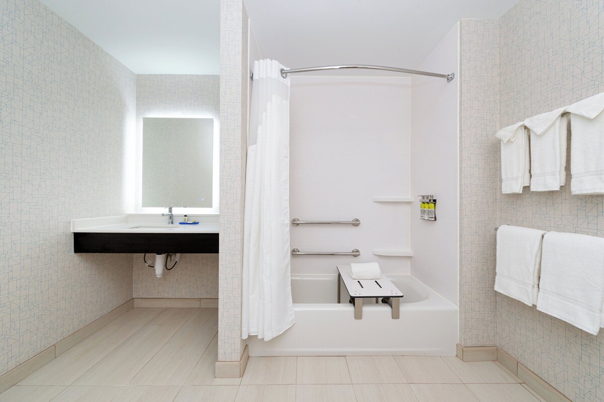 Een moderne badkamer met een douche, wastafel en spiegel.