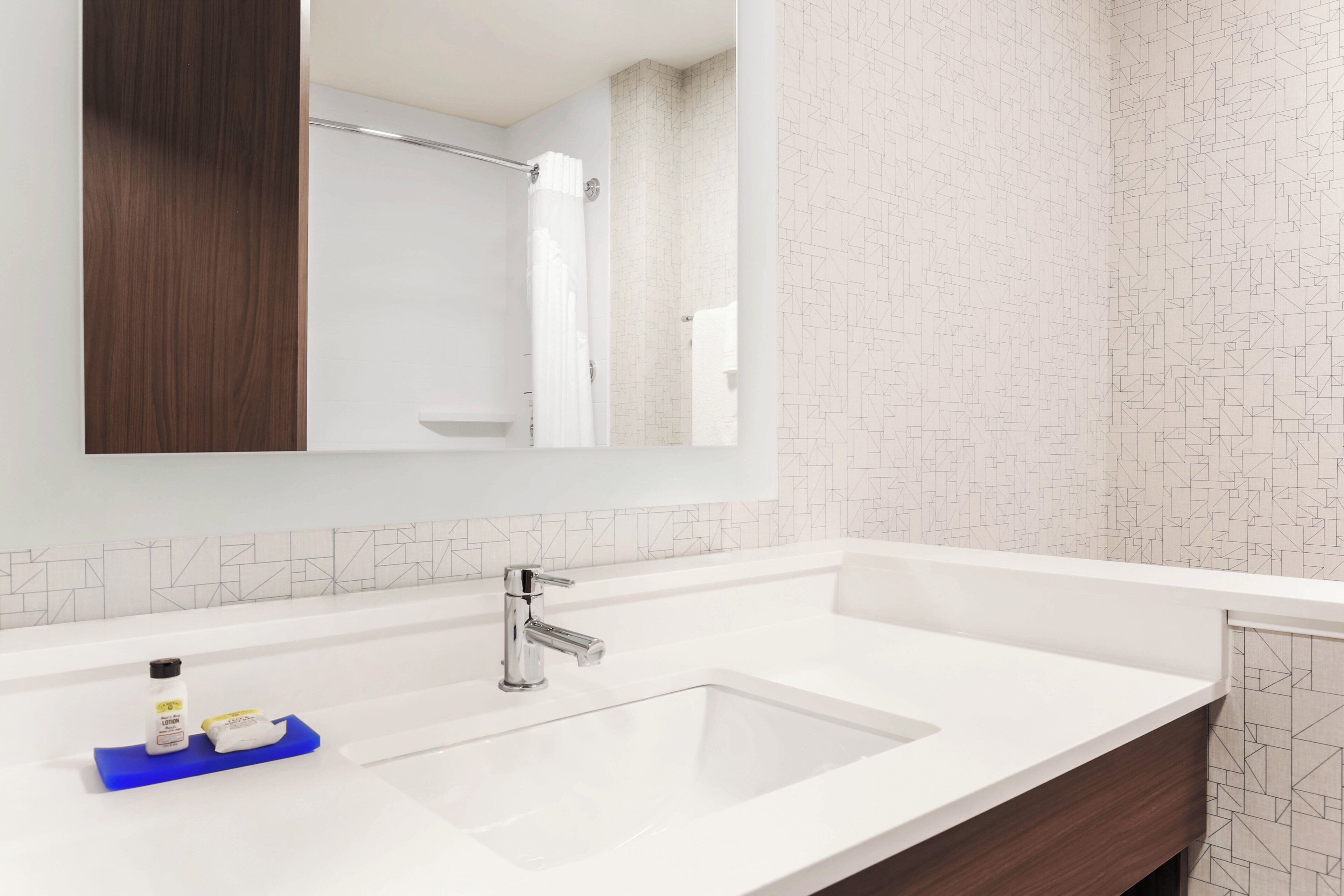 Un baño moderno con lavamanos blanco, grifo cromado y un espejo encima.
