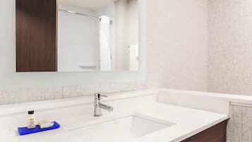 Un baño moderno con lavamanos blanco, grifo cromado y un espejo encima.