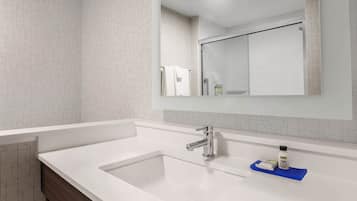 A modern bathroom with a white sink, a mirror above it, and a towel hanging on a rack.