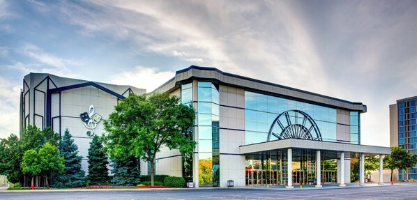 A modern building with a large glass facade, a prominent circular structure on the right, and a landscaped entrance area. - Holiday Inn Express & Suites Chicago O'Hare Airport by IHG (Des Plaines)