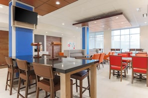 Un comedor moderno con una mesa central, sillas y una zona de cocina al fondo.
