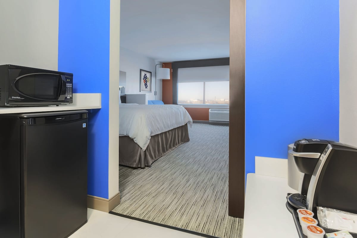Una habitación de hotel con cama, microondas, refrigerador y cafetera.