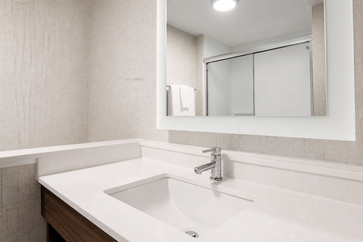 A bathroom with a white sink, a mirror, and a towel rack.