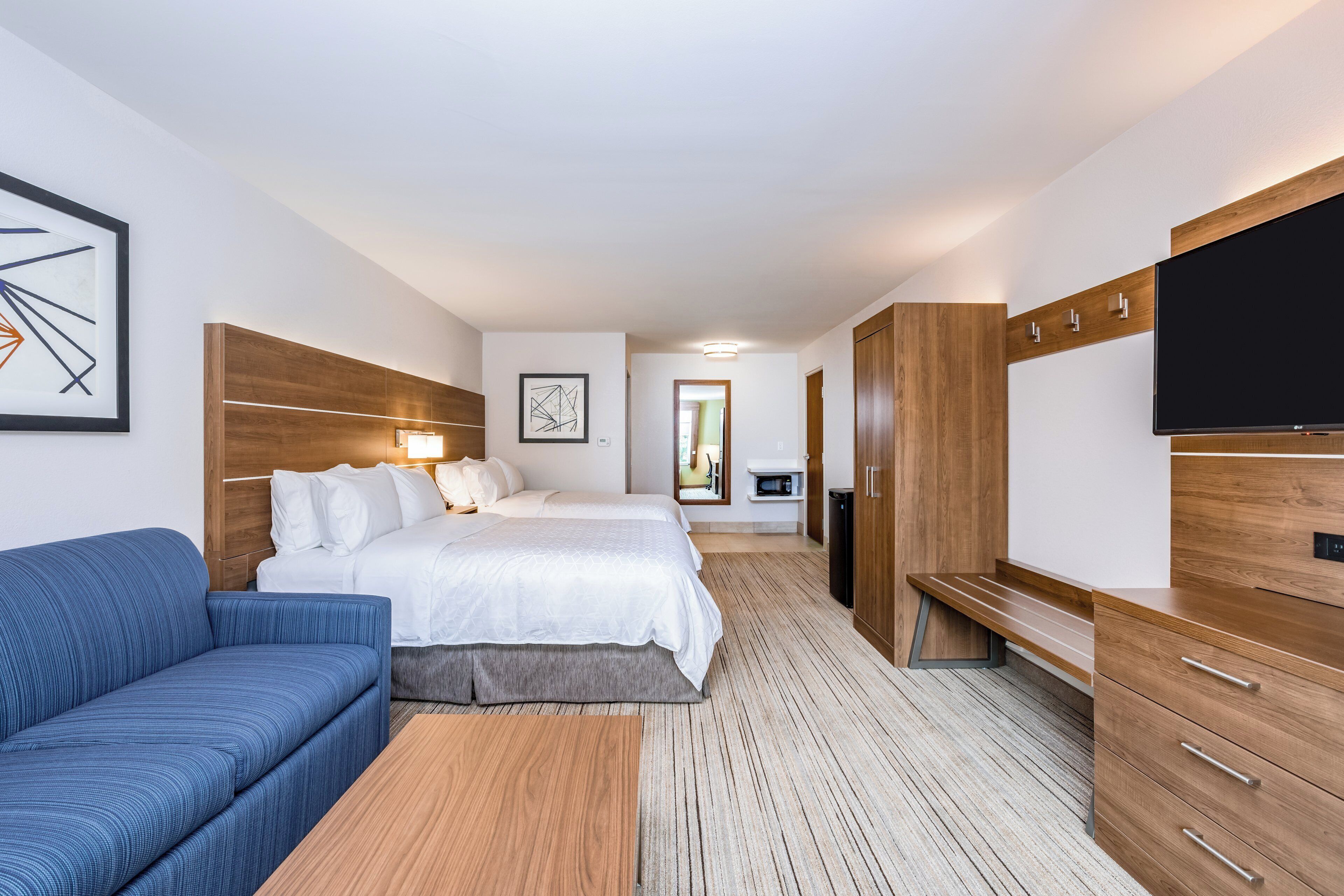 Une chambre d’hôtel avec un lit, un canapé, une télévision et un bureau.