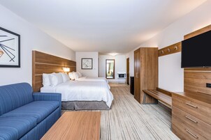 A hotel room with a bed, a sofa, a TV, and a desk.