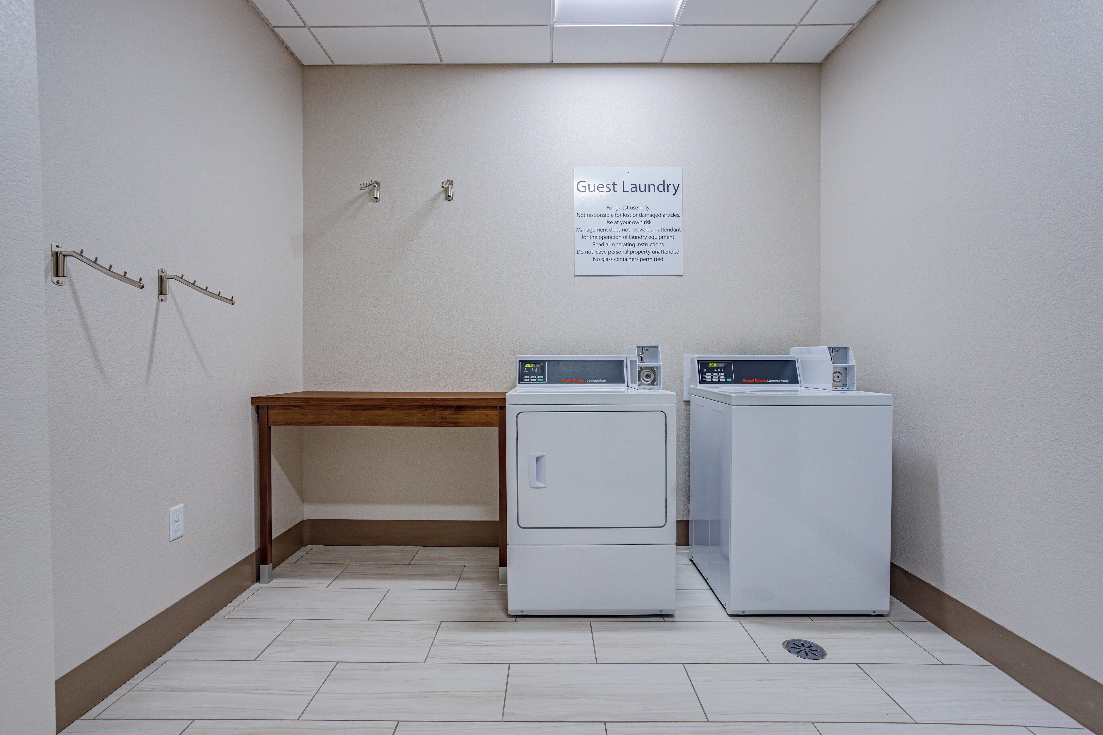 A laundry area with two washers and a dryer, a bench, and a sign indicating it's for guest use only.
