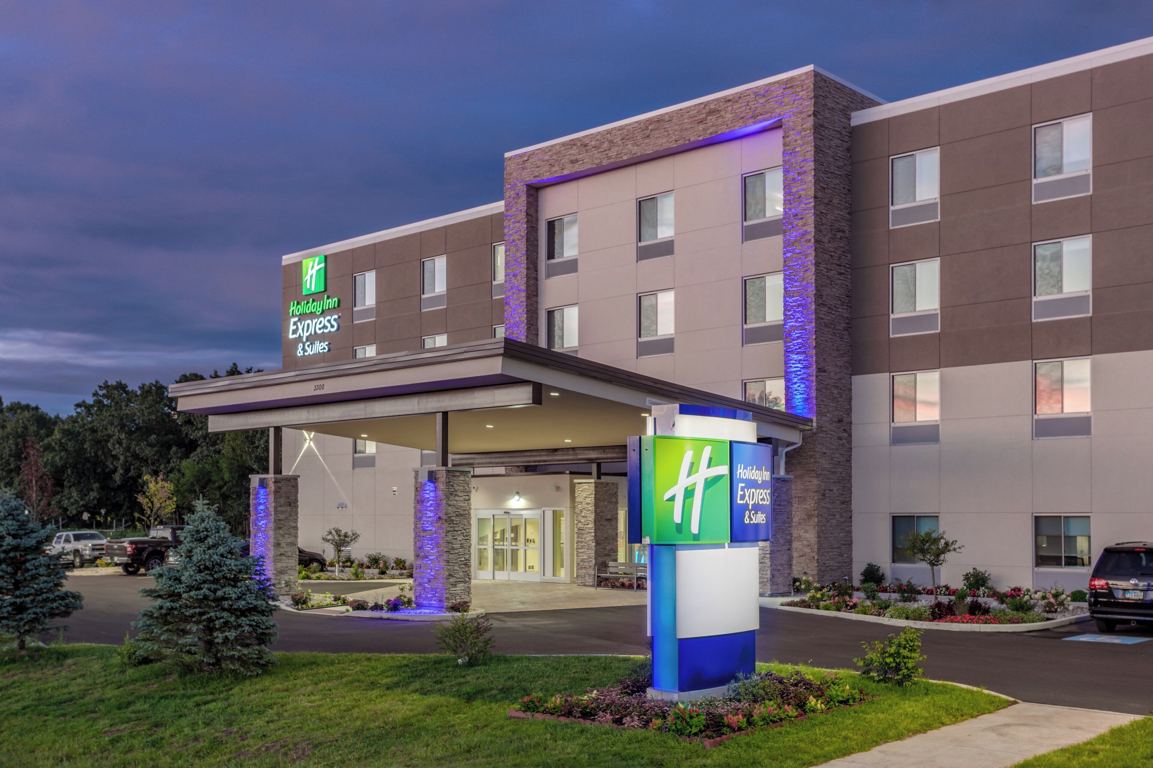 A Holiday Inn Express & Suites hotel with a covered entrance, multiple floors, and a landscaped front yard.