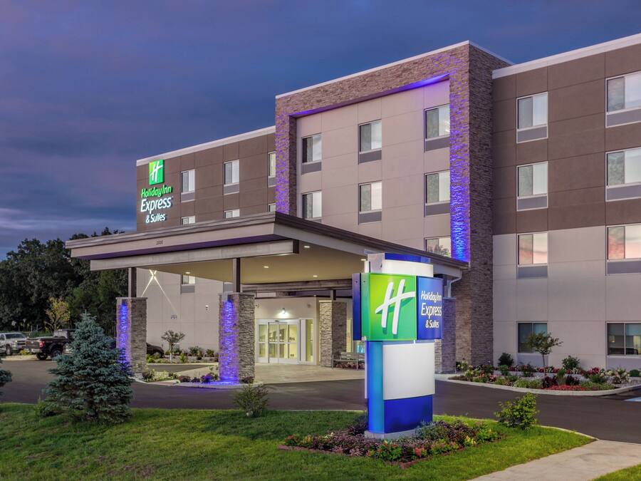 Un hôtel Holiday Inn Express & Suites doté d’une entrée couverte, de plusieurs étages et d’un parterre aménagé à l’avant.