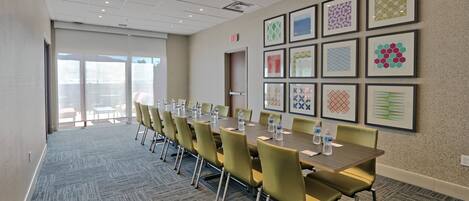 A conference room with a long table, chairs, and framed artwork on the walls.