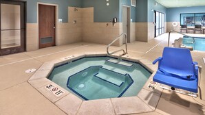 Uma pequena piscina interna com uma cadeira azul e uma cadeira salva-vidas, cercada por azulejos bege e paredes azuis.