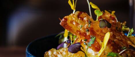 A close-up of a dish with a blue bowl, garnished with herbs and edible flowers.