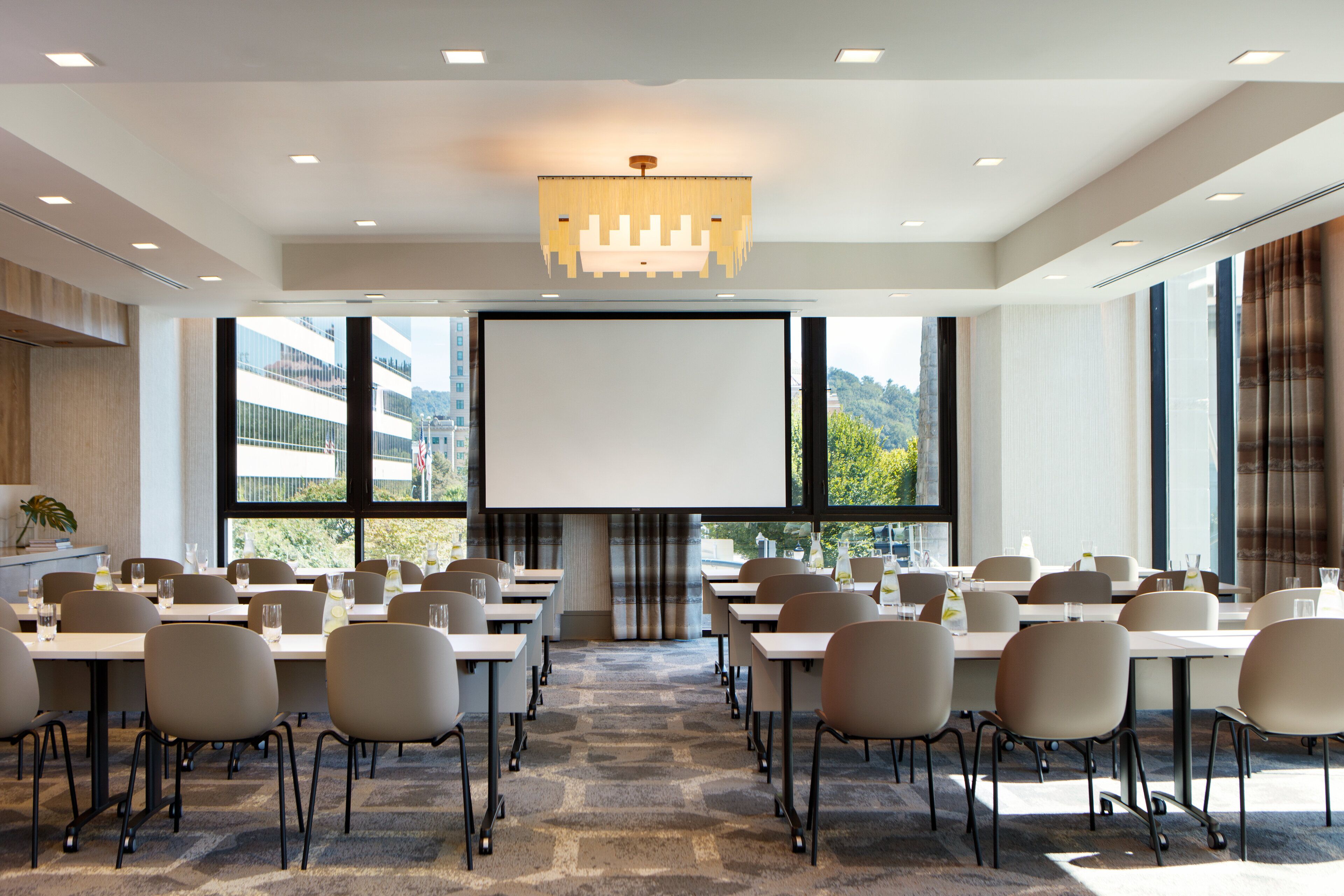 A conference room with a large screen, multiple tables, and chairs arranged for a meeting.