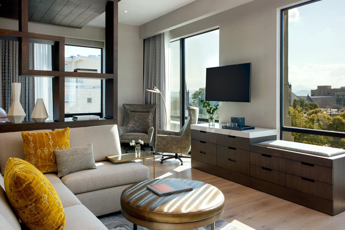 A modern living room with a sofa, armchairs, a coffee table, and a TV mounted on the wall.