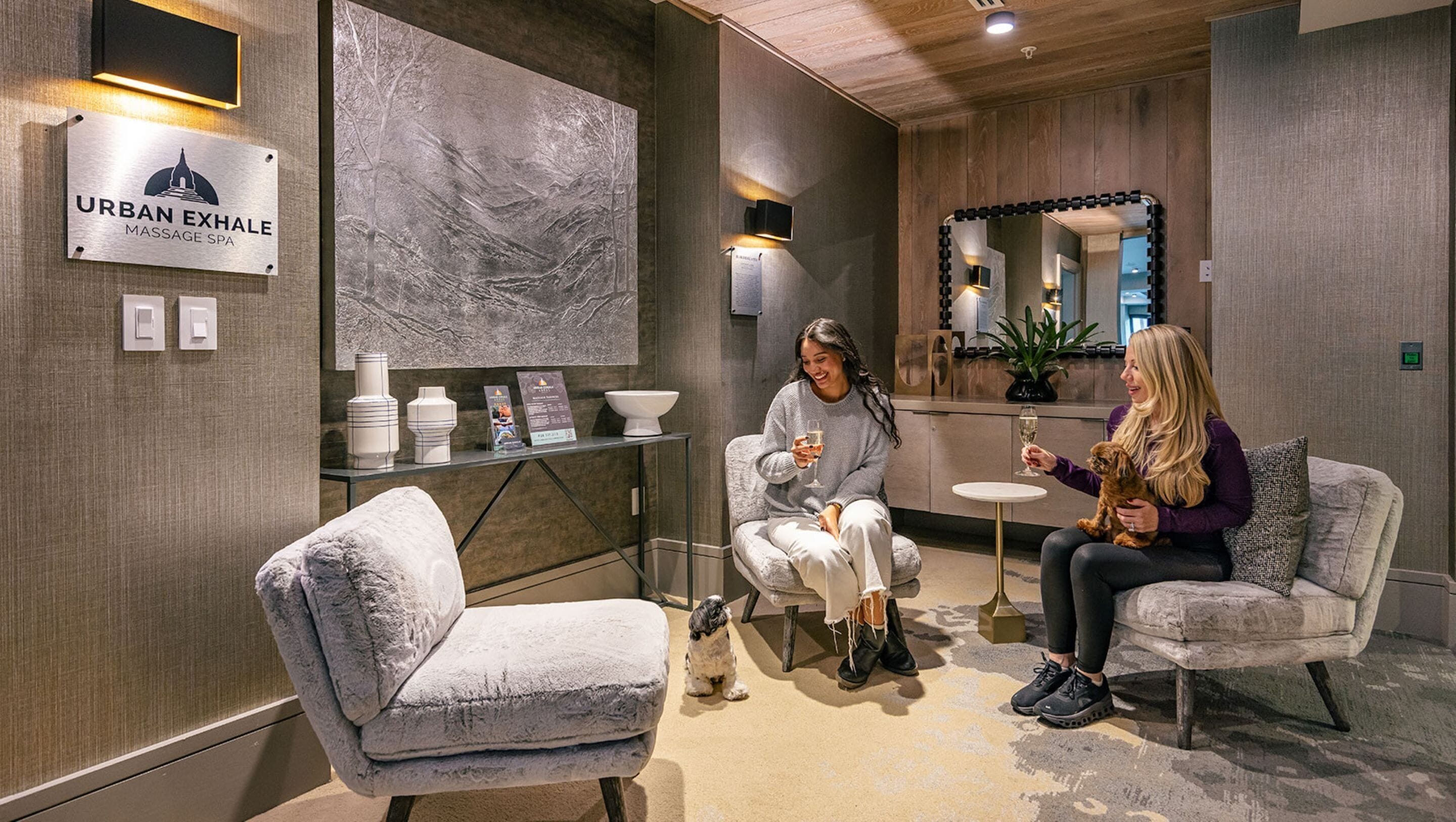 A massage spa interior with a reception desk, a large abstract wall art, and a seating area with a dog.