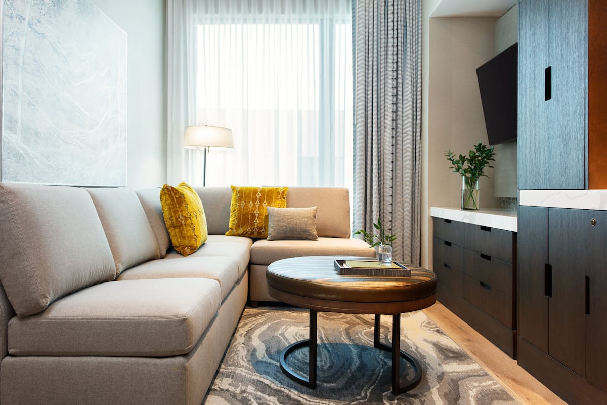 A modern living room with a sofa, a round coffee table, and a TV mounted on the wall.